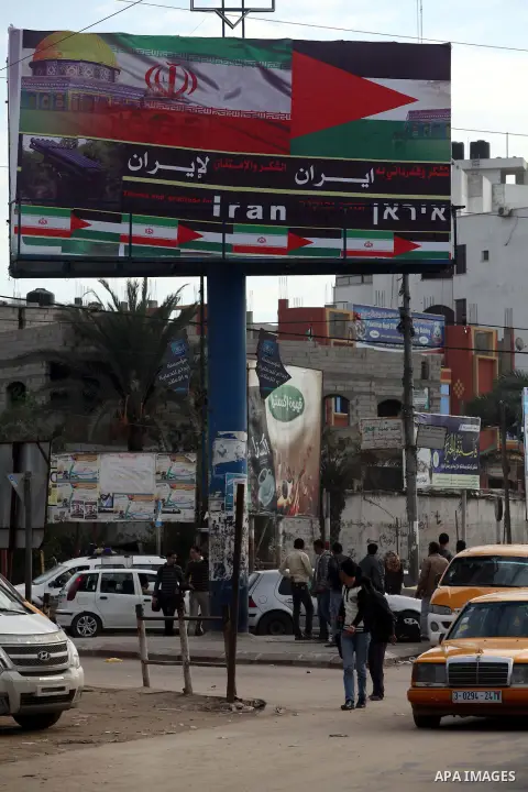 Palestinians walk next to a placard reads in Arabic "Thanks for Iran" in Gaza city on November 27, 2012. The commander of Iran's elite Revolutionary Guards has publicly admitted that his forces supplied the Islamic milit...