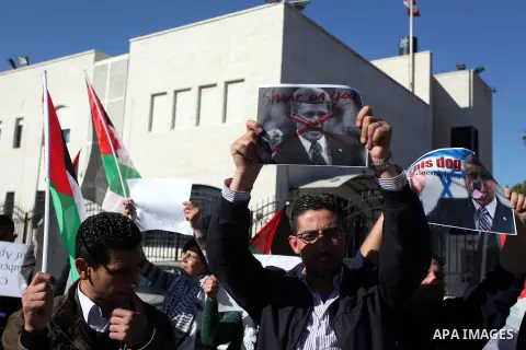 Palestinians hold national flags and a poster of Canadian Prime Minister Stephen Harper superimposed with a face of a dog during a protest following his remarks about the Palestinian UN bid for an observer state status,...