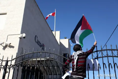A Palestinian activist hoists the Palestinian flag on top the Canadian representative office fence during a protest following his remarks about the Palestinian UN bid for an observer state status, in front of Canadian re...