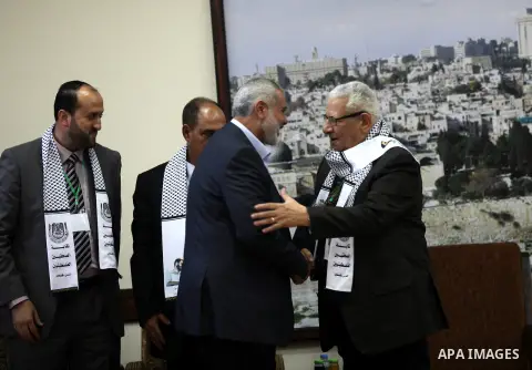 Palestinian Prime Minister in Gaza strip Ismail Haniyeh shakes hands with Makram Ahmed, the Secretary General of the Arab Journalists Union during his visit in Gaza city on November 28, 2012. Israeli aircraft killed 3 an...