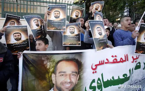Palestinian protesters hold portraits of Samer Issawi, a Palestinian prisoner held in an Israeli jail and on hunger strike since August 1, during a solidarity sit-in outside the Red Cross offices in Jerusalem, on Novembe...