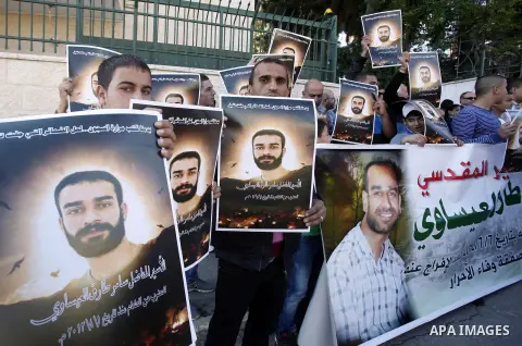 Palestinian protesters hold portraits of Samer Issawi, a Palestinian prisoner held in an Israeli jail and on hunger strike since August 1, during a solidarity sit-in outside the Red Cross offices in Jerusalem, on Novembe...