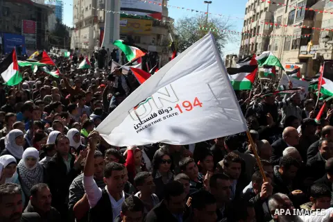 Palestinians wave their national flag during a rally in the West Bank city of Ramallah on November 29, 2012 to support Palestinian leader Mahmud Abbas who is heading to the United Nations General Assembly today with huge...