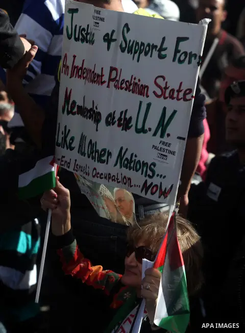 Palestinians wave their national flag during a rally in the West Bank city of Ramallah on November 29, 2012 to support Palestinian leader Mahmud Abbas who is heading to the United Nations General Assembly today with huge...