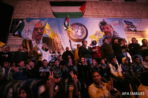 Palestinians wave their national flag during the speech of President Mahmoud Abbas in the U.N. General Assembly, in the West Bank city of Hebron, November 29, 2012. The 193-nation U.N. General Assembly overwhelmingly app...