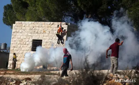 Palestinian protesters hurl stones at Israeli security forces during a protest against the expansion of the nearby Jewish settlement of Halamish, in the West Bank village of Nabi Saleh near Ramallah, Friday, Nov. 30, 201...