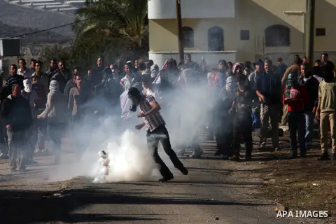 A Palestinian protester kicks a tear gas canister at Israeli soldiers on the sidelines of a demonstration against the expropriations by Israel in the West Bank village of Kafr Qaddum, near Nablus, on November 30, 2012. P...