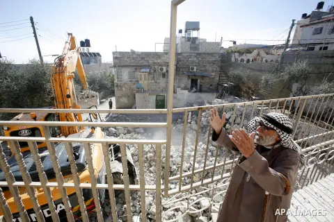 A Palestinian man watchs as an Israeli bulldozer destroys a home in East Jerusalem district of Sur Baher on December 1, 2012 after an Israeli court ruled that the house was built without a municipality permit. Many Pales...