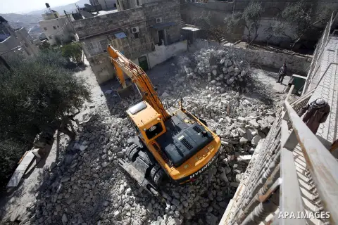 Palestinians watch as an Israeli bulldozer destroys a home in East Jerusalem district of Sur Baher on December 1, 2012 after an Israeli court ruled that the house was built without a municipality permit. Many Palestinian...