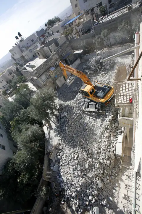 An Israeli bulldozer destroys a home in East Jerusalem district of Sur Baher on December 1, 2012 after an Israeli court ruled that the house was built without a municipality permit. Many Palestinians end up demolishing t...