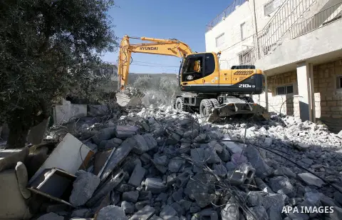 An Israeli bulldozer destroys a home in East Jerusalem district of Sur Baher on December 1, 2012 after an Israeli court ruled that the house was built without a municipality permit. Many Palestinians end up demolishing t...