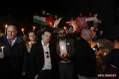 Palestinian and foreign activists hold candles during a solidarity march with the Dalu family next to their house, as well as a wrecked car festooned with candles, which was hit by an Israeli strike during Israel's recen...
