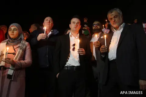Palestinian and foreign activists hold candles during a solidarity march with the Dalu family next to their house, as well as a wrecked car festooned with candles, which was hit by an Israeli strike during Israel's recen...