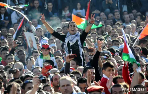 Palestinians wave national flags as they celebrate their successful bid for UN non-member observer state status, in the West Bank city of Ramallah on December 2, 2012, Palestinian President Mahmoud Abbas arrived to the W...