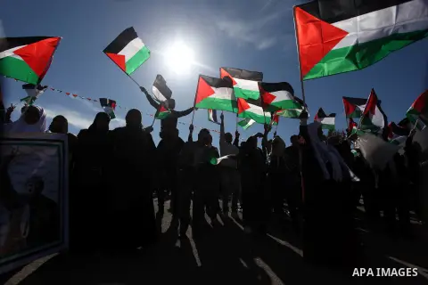 Palestinians wave national flags as they celebrate their successful bid for UN non-member observer state status, in the West Bank city of Ramallah on December 2, 2012, Palestinian President Mahmoud Abbas arrived to the W...
