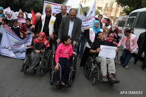 Palestinian children with special needs walk past buildings destroyed during the Gaza-Israeli conflict during a demonstration on the occasion of the UN International Day of People with Disability, on December 4, 2012 in...