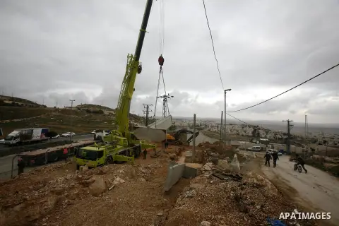 Israeli laborers install concrete sections during the construction of the separation barrier wall in the Palestinian neighborhood of Shuafat in East Jerusalem, 05 Dec, 2012. Photo by Mahfouz Abu Turk