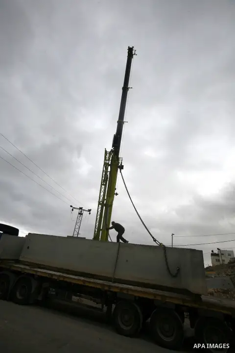 Israeli laborers install concrete sections during the construction of the separation barrier wall in the Palestinian neighborhood of Shuafat in East Jerusalem, 05 Dec, 2012. Photo by Mahfouz Abu Turk