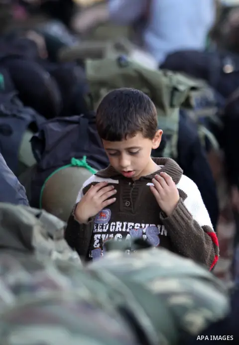 A Palestinian boy attends Friday prayer next to members of the Ezzedine al-Qassam brigade, the armed wing Hamas, as they prepare for the arrival of the Islamist movement's exiled politburo chief Khaled Meshaal who is due...