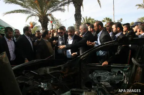 Hamas chief Khaled Meshaal speaks with Palestinian prime minister in the Gaza Strip, Ismail Haniya near the targeted car of Hamas militant leader Ahmed Al-Gabery upon Meshaal's arrival in Rafah, southern Gaza, on Decembe...
