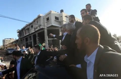 Hamas chief Khaled Meshaal, riding in a car with Palestinian prime minister in Gaza Strip Ismail Haniyeh, waves to the crowd upon his arrival in Gaza City December 7, 2012. Meshaal is making his first-ever visit to the G...