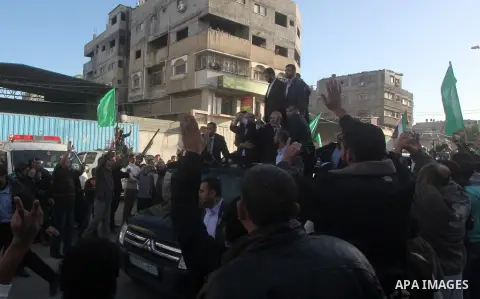 Hamas chief Khaled Meshaal, riding in a car with Palestinian prime minister in Gaza Strip Ismail Haniyeh, waves to the crowd upon his arrival in Gaza City December 7, 2012. Meshaal is making his first-ever visit to the G...