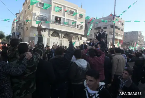 Hamas chief Khaled Meshaal, riding in a car with Palestinian prime minister in Gaza Strip Ismail Haniyeh, waves to the crowd upon his arrival in Gaza City December 7, 2012. Meshaal is making his first-ever visit to the G...