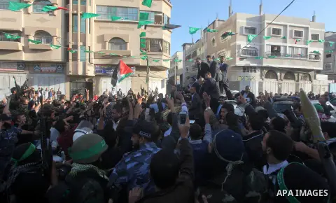 Hamas chief Khaled Meshaal, riding in a car with Palestinian prime minister in Gaza Strip Ismail Haniyeh, waves to the crowd upon his arrival in Gaza City December 7, 2012. Meshaal is making his first-ever visit to the G...