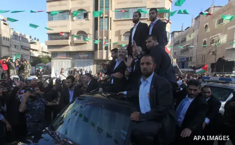 Hamas chief Khaled Meshaal, riding in a car with Palestinian prime minister in Gaza Strip Ismail Haniyeh, waves to the crowd upon his arrival in Gaza City December 7, 2012. Meshaal is making his first-ever visit to the G...