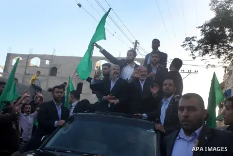 Hamas chief Khaled Meshaal, riding in a car with Palestinian prime minister in Gaza Strip Ismail Haniyeh, waves to the crowd upon his arrival in Gaza City December 7, 2012. Meshaal is making his first-ever visit to the G...