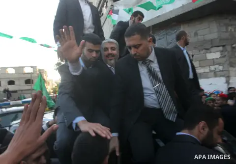 Hamas chief Khaled Meshaal, riding in a car with Palestinian prime minister in Gaza Strip Ismail Haniyeh, waves to the crowd upon his arrival in Gaza City December 7, 2012. Meshaal is making his first-ever visit to the G...