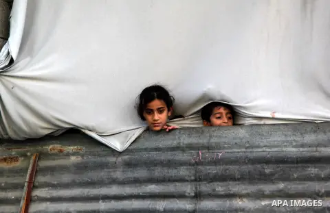 Palestinian children watch as Hamas chief Khaled Meshaal arrives in Gaza City December 7, 2012. Meshaal is making his first-ever visit to the Gaza Strip amid tight security for festivities marking the ruling Islamist mov...