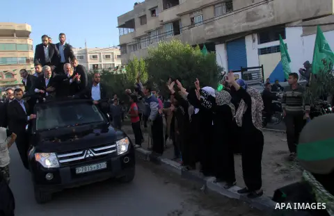 Hamas chief Khaled Meshaal, riding in a car with Palestinian prime minister in Gaza Strip Ismail Haniyeh, waves to the crowd upon his arrival in Gaza City December 7, 2012. Meshaal is making his first-ever visit to the G...