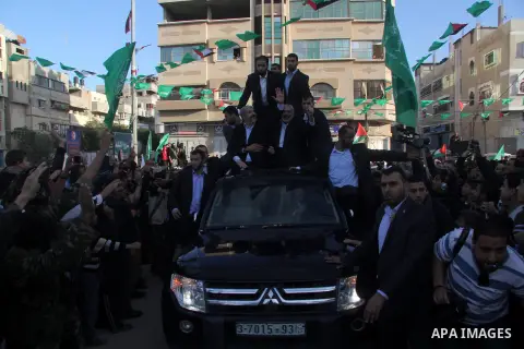 Hamas chief Khaled Meshaal, riding in a car with Palestinian prime minister in Gaza Strip Ismail Haniyeh, waves to the crowd upon his arrival in Gaza City December 7, 2012. Meshaal is making his first-ever visit to the G...
