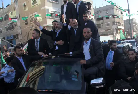 Hamas chief Khaled Meshaal, riding in a car with Palestinian prime minister in Gaza Strip Ismail Haniyeh, waves to the crowd upon his arrival in Gaza City December 7, 2012. Meshaal is making his first-ever visit to the G...