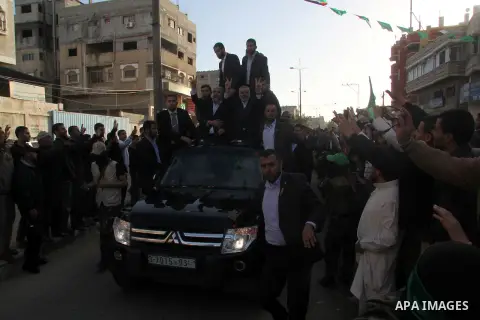 Hamas chief Khaled Meshaal, riding in a car with Palestinian prime minister in Gaza Strip Ismail Haniyeh, waves to the crowd upon his arrival in Gaza City December 7, 2012. Meshaal is making his first-ever visit to the G...