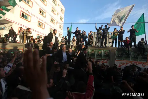 Hamas chief Khaled Meshaal, riding in a car with Palestinian prime minister in Gaza Strip Ismail Haniyeh, waves to the crowd upon his arrival in Gaza City December 7, 2012. Meshaal is making his first-ever visit to the G...