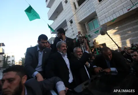 Hamas chief Khaled Meshaal, riding in a car with Palestinian prime minister in Gaza Strip Ismail Haniyeh, waves to the crowd upon his arrival in Gaza City December 7, 2012. Meshaal is making his first-ever visit to the G...