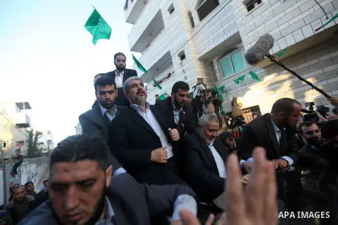 Hamas chief Khaled Meshaal, riding in a car with Palestinian prime minister in Gaza Strip Ismail Haniyeh, waves to the crowd upon his arrival in Gaza City December 7, 2012. Meshaal is making his first-ever visit to the G...