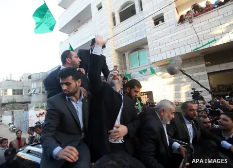 Hamas chief Khaled Meshaal, riding in a car with Palestinian prime minister in Gaza Strip Ismail Haniyeh, waves to the crowd upon his arrival in Gaza City December 7, 2012. Meshaal is making his first-ever visit to the G...