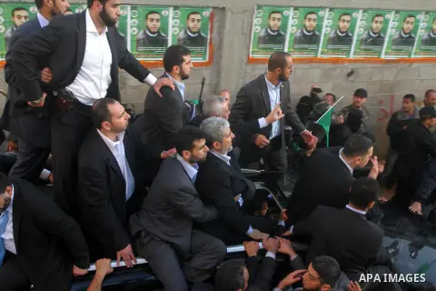 Hamas chief Khaled Meshaal, riding in a car with Palestinian prime minister in Gaza Strip Ismail Haniyeh, waves to the crowd upon his arrival in Gaza City December 7, 2012. Meshaal is making his first-ever visit to the G...