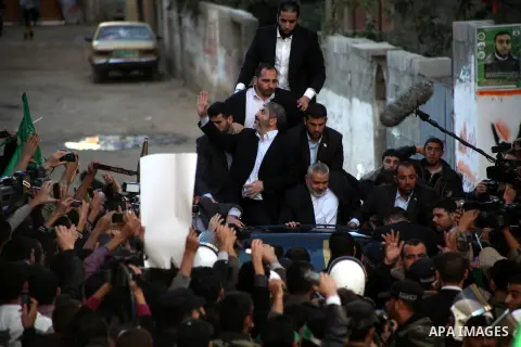 Hamas chief Khaled Meshaal, riding in a car with Palestinian prime minister in Gaza Strip Ismail Haniyeh, waves to the crowd upon his arrival in Gaza City December 7, 2012. Meshaal is making his first-ever visit to the G...
