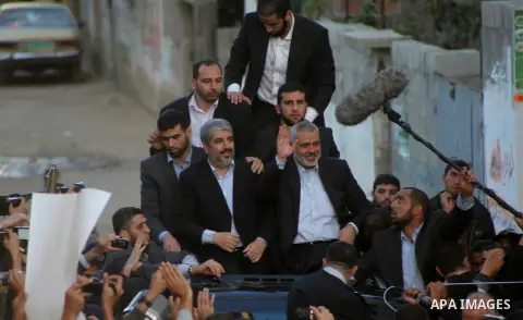 Hamas chief Khaled Meshaal, riding in a car with Palestinian prime minister in Gaza Strip Ismail Haniyeh, waves to the crowd upon his arrival in Gaza City December 7, 2012. Meshaal is making his first-ever visit to the G...