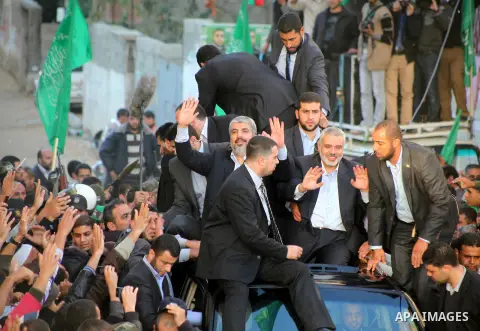Hamas chief Khaled Meshaal, riding in a car with Palestinian prime minister in Gaza Strip Ismail Haniyeh, waves to the crowd upon his arrival in Gaza City December 7, 2012. Meshaal is making his first-ever visit to the G...