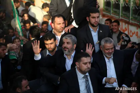 Hamas chief Khaled Meshaal, riding in a car with Palestinian prime minister in Gaza Strip Ismail Haniyeh, waves to the crowd upon his arrival in Gaza City December 7, 2012. Meshaal is making his first-ever visit to the G...