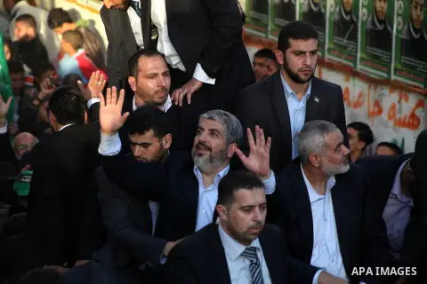 Hamas chief Khaled Meshaal, riding in a car with Palestinian prime minister in Gaza Strip Ismail Haniyeh, waves to the crowd upon his arrival in Gaza City December 7, 2012. Meshaal is making his first-ever visit to the G...