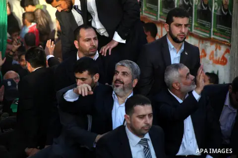 Hamas chief Khaled Meshaal, riding in a car with Palestinian prime minister in Gaza Strip Ismail Haniyeh, waves to the crowd upon his arrival in Gaza City December 7, 2012. Meshaal is making his first-ever visit to the G...