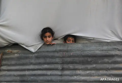 Palestinian children watch as Hamas chief Khaled Meshaal arrives in Gaza City December 7, 2012. Meshaal is making his first-ever visit to the Gaza Strip amid tight security for festivities marking the ruling Islamist mov...