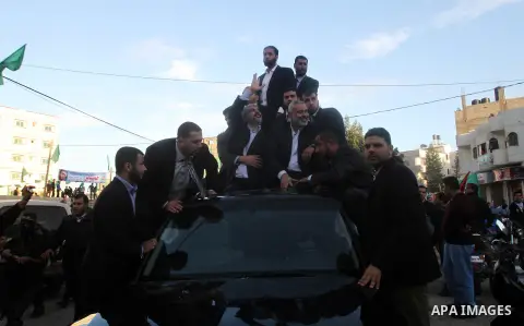 Hamas chief Khaled Meshaal, riding in a car with Palestinian prime minister in Gaza Strip Ismail Haniyeh, waves to the crowd upon his arrival in Gaza City December 7, 2012. Meshaal is making his first-ever visit to the G...