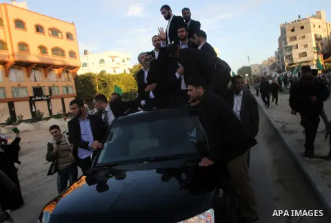 Hamas chief Khaled Meshaal, riding in a car with Palestinian prime minister in Gaza Strip Ismail Haniyeh, waves to the crowd upon his arrival in Gaza City December 7, 2012. Meshaal is making his first-ever visit to the G...